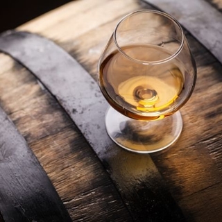 Glas Whiskey steht auf einem Fass.