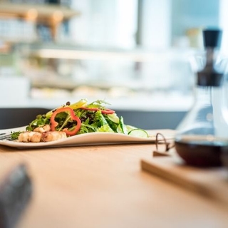 Teller mit grünem Salat, Paprika und gegrilltem Schafkäse im Speckmantel.