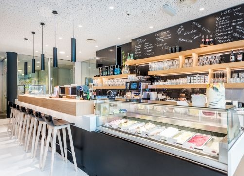 Blick auf den Thekenbereich von NOVA - das Café. Zu sehen ist eine Eisvitrine, die Theke sowie Barhocker.