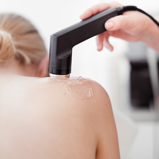 Eine Frau erhält eine Ultraschalltherapie am Rücken