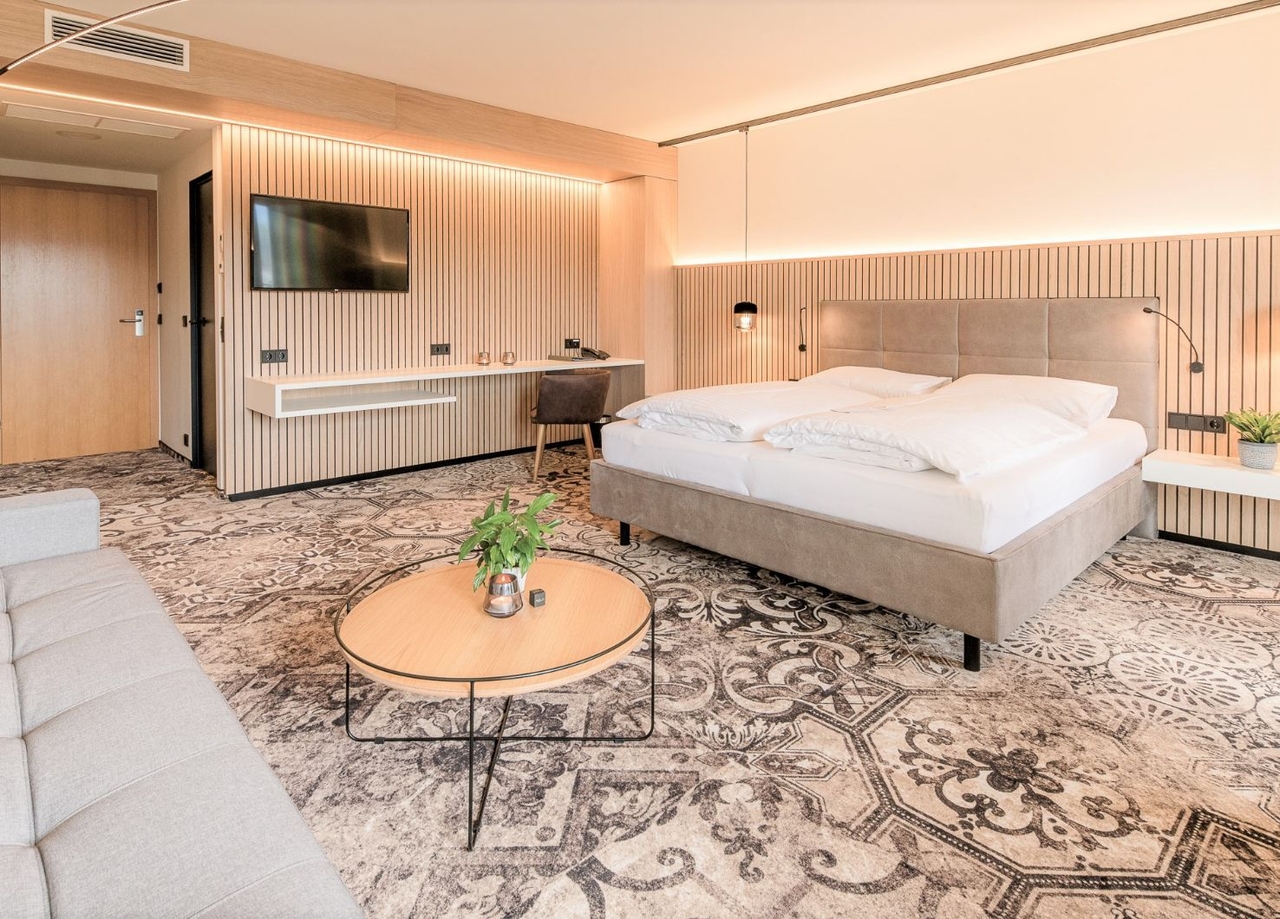 Blick in die Junior Suite vom Hotel NOVA. Zu sehen ist ein Doppelbett und ein Schreibtisch inkl. Stuhl.