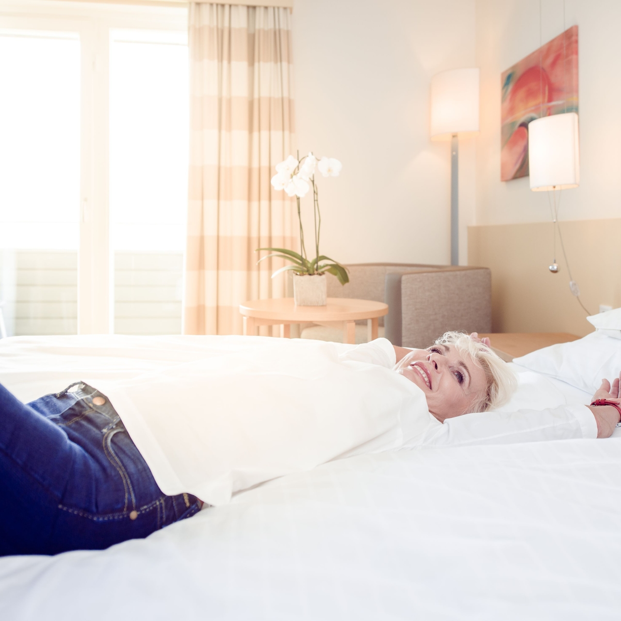 Dame liegt im Hotelbett und lächelt. 