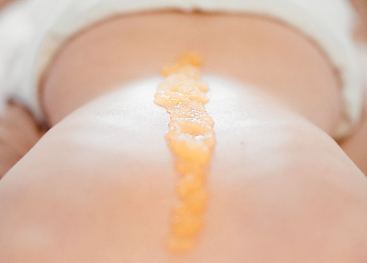 Meersalzmassage: Dame liegt am Bauch, entlang ihrer Wirbelsäule ist das Salz für die Massage aufgetragen.