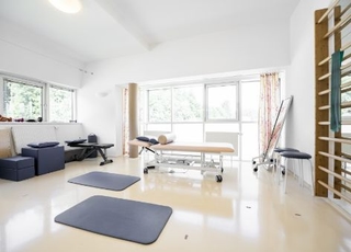 Blick in den Gymnastikraum für die Einzelheilgymnastik. Zu sehen ist eine Liege, Trainingsmatten sowie eine Sprossenleiter.