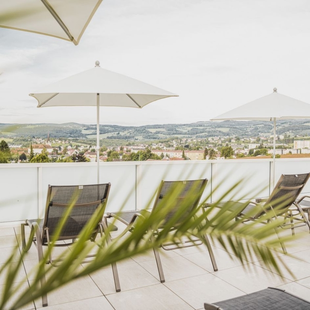 Blick auf das Saunadach der Therme NOVA. Zu sehen sind drei Liegestühle, und ein Schirm.