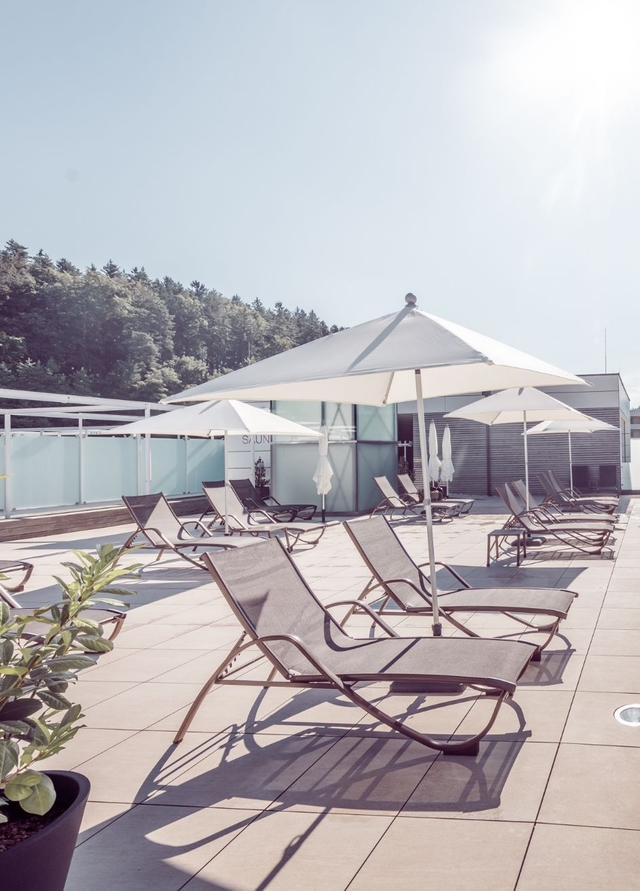 Blick auf das Saunadach der Therme NOVA. Zu sehen sind drei Liegestühle, und ein Schirm.