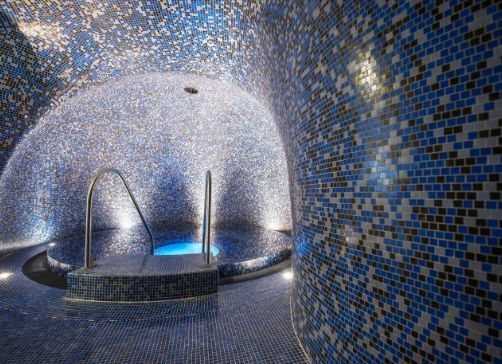 Blick in die Blaue Grotte der Therme NOVA. Zu sehen sind die kleinen blauen Mosaikfließen und der Abgang ins runde Becken der Grotte. 