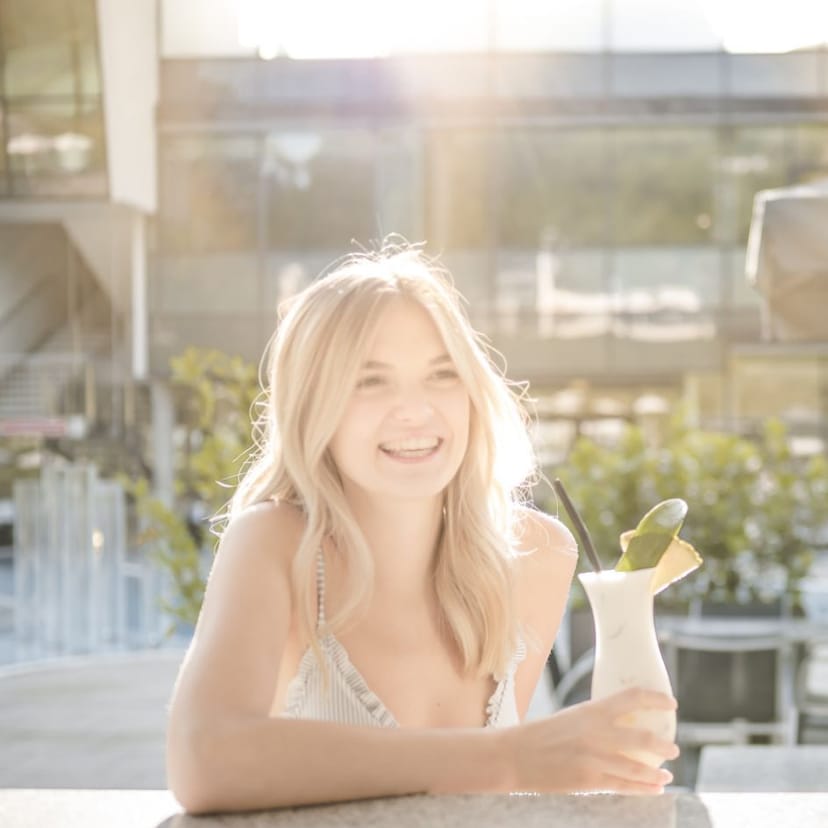 Frau sitzt an der Bar in der Therme NOVA mit einem Cocktail in der Hand.
