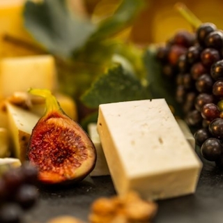 Blick auf eine Käseplatte. Zu sehen sind Käsesorten, Feigen und Weintrauben.