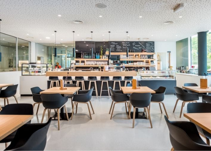 Blick in das NOVA-das Café. Zu sehen ist der Thekenbereich und Tische mit Stühlen.