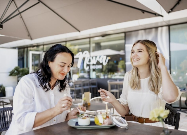 Zwei Damen sitzen auf der Terrasse vom NOVA-das Café und genießen gemeinsam ein Dessert. 