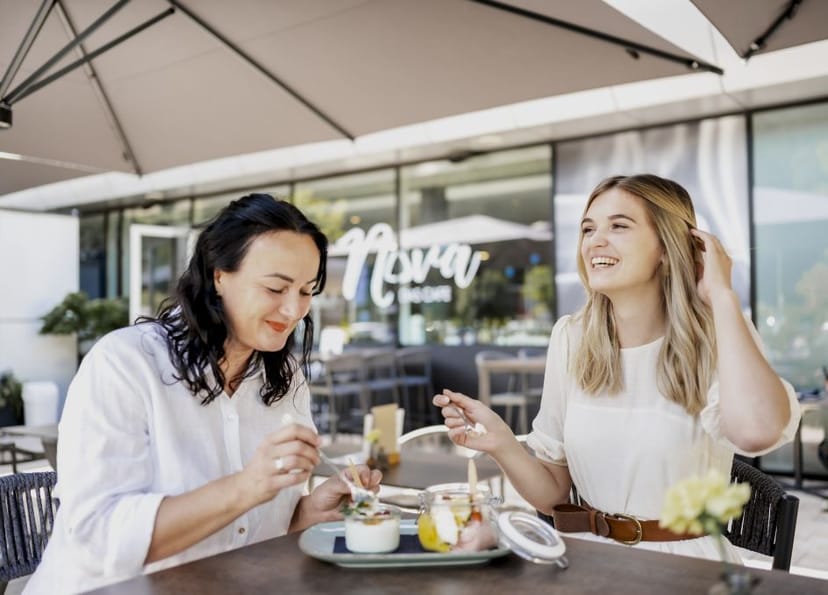 Zwei Damen sitzen auf der Terrasse vom NOVA-das Café und genießen gemeinsam ein Dessert.