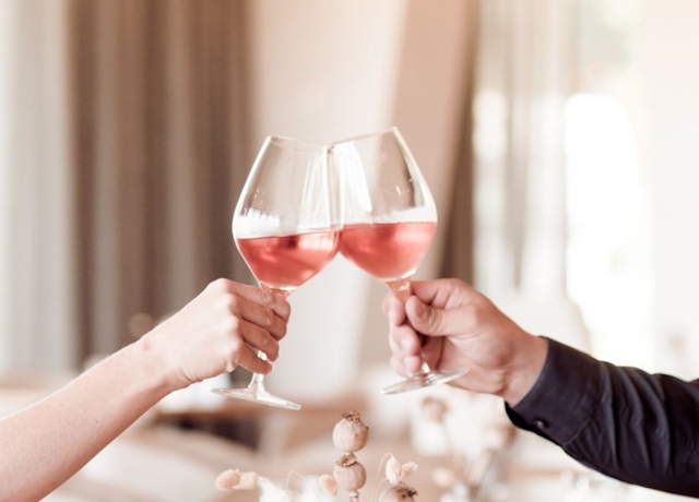 Zu sehen sind zwei Hände mit jeweils einem Glas Rosé Wein, die gerade anstoßen.