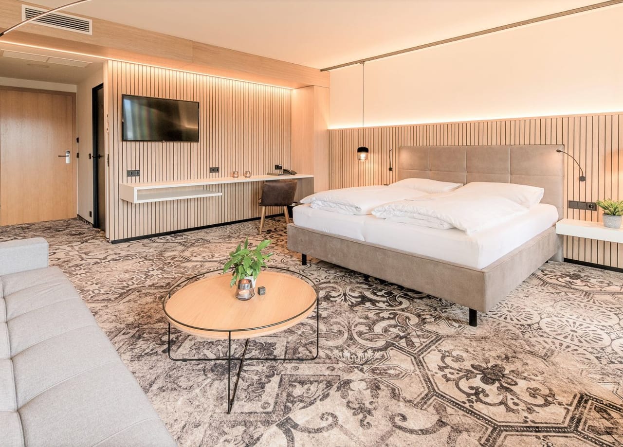 Blick in die Junior Suite vom Hotel NOVA. Zu sehen ist ein Doppelbett und ein Schreibtisch inkl. Stuhl.
