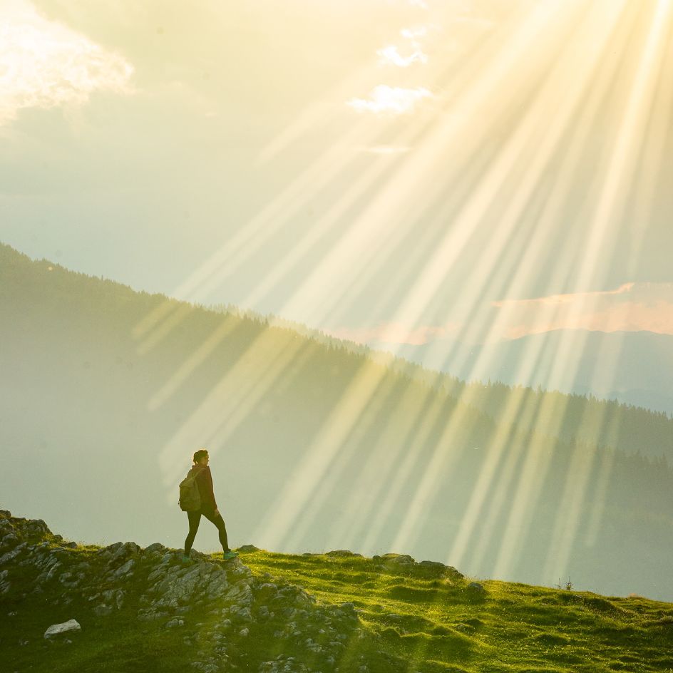 Person steht auf einem Hügel und blickt auf die umliegende Landschaft.