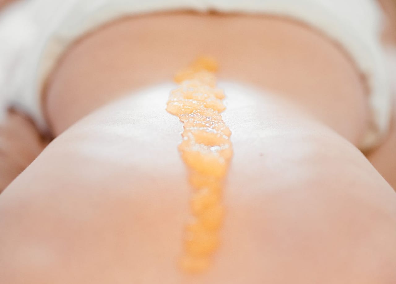 Meersalzmassage: Dame liegt am Bauch, entlang ihrer Wirbelsäule ist das Salz für die Massage aufgetragen.