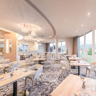 Blick ins Panorama-Restaurant von Hotel & Therme NOVA. Zu sehen sind gedeckte Tische.
