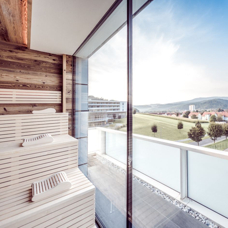 Blick durch das Panoramafenster der Stubalmsauna auf das Gebäude vom Hotel NOVA.
